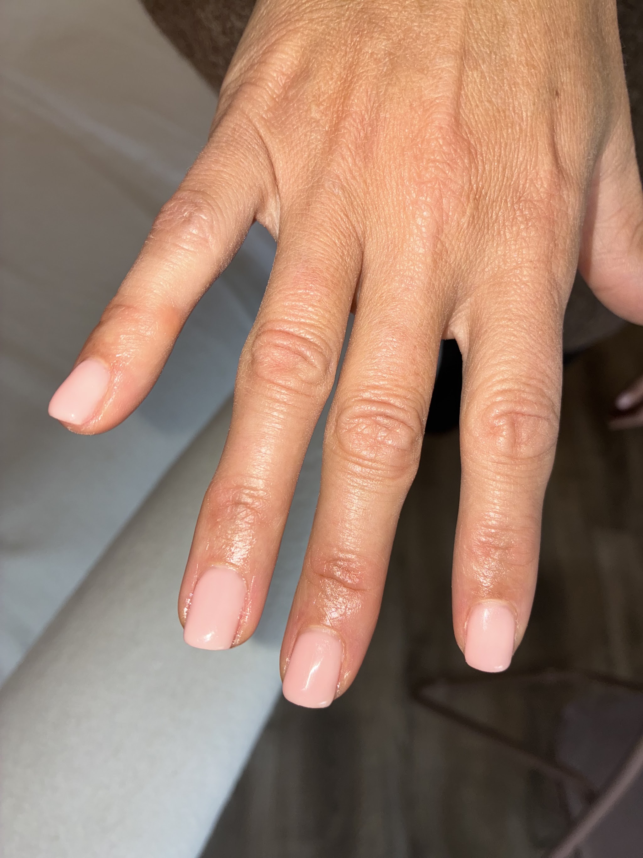 Hand met natuurlijk roze gelakte nagels