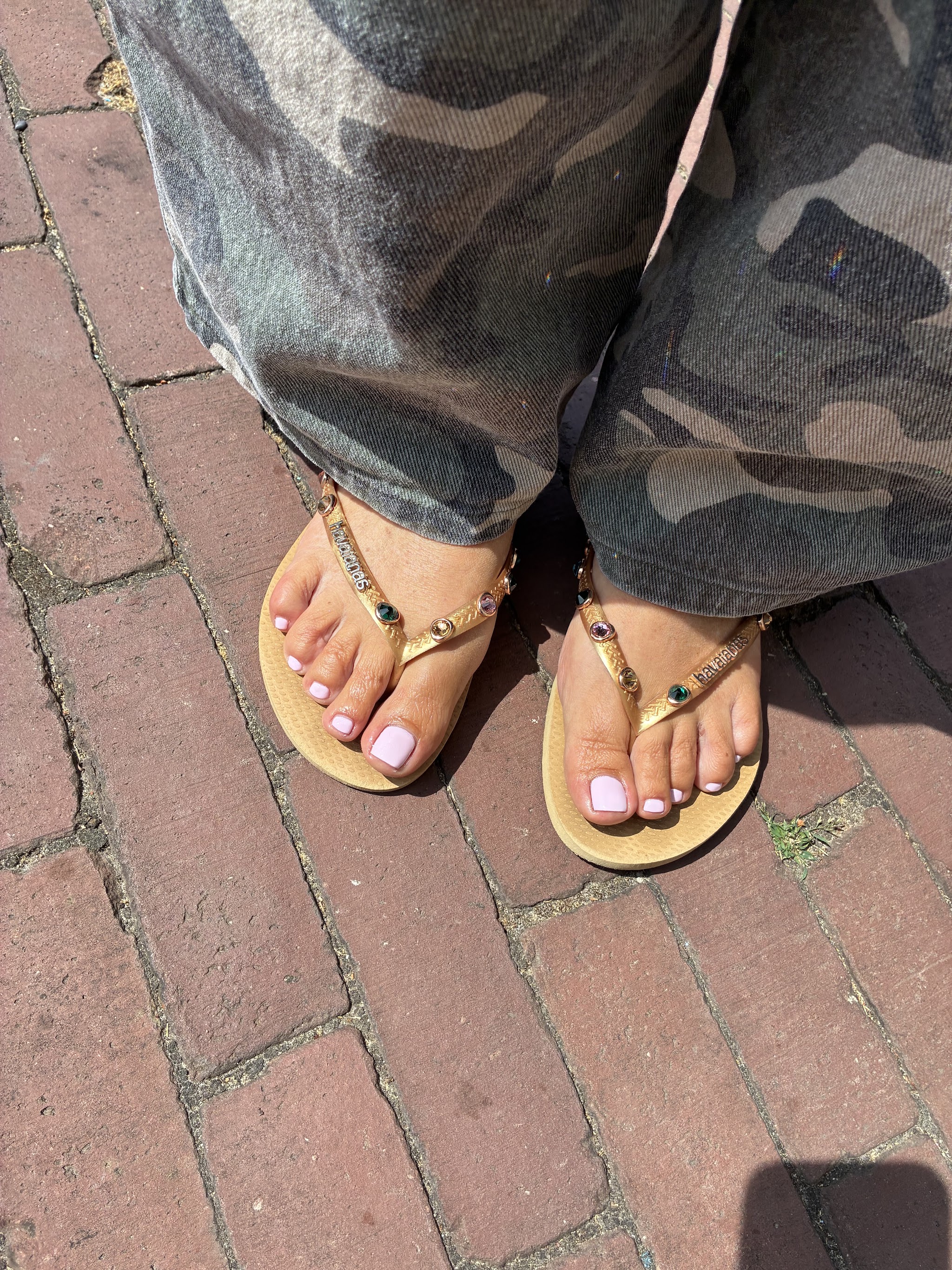 Voeten in gouden sandalen met lichtroze teennagels