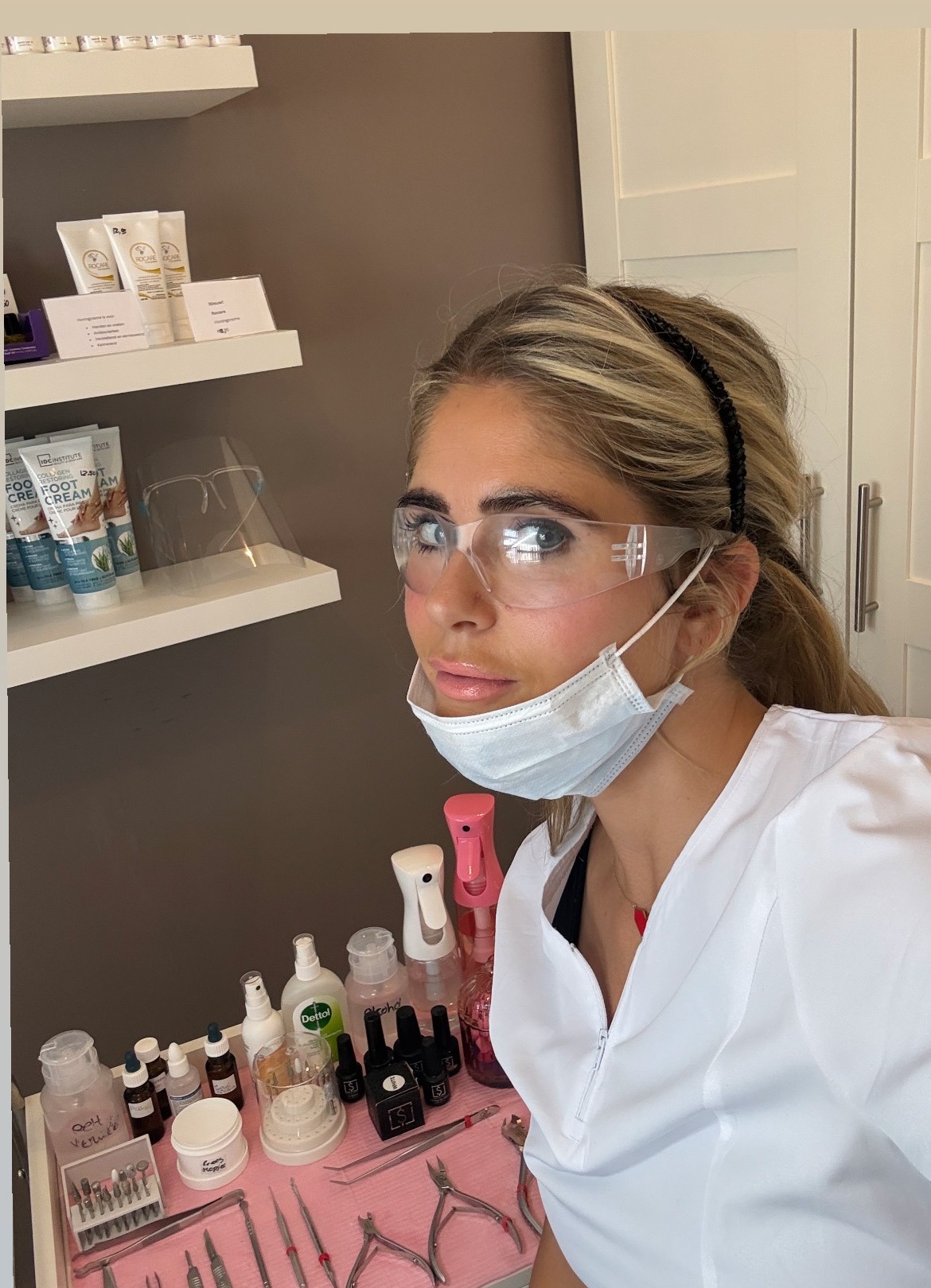 Nena in witte werkkleding in de salon, met haar instrumenten voor zich