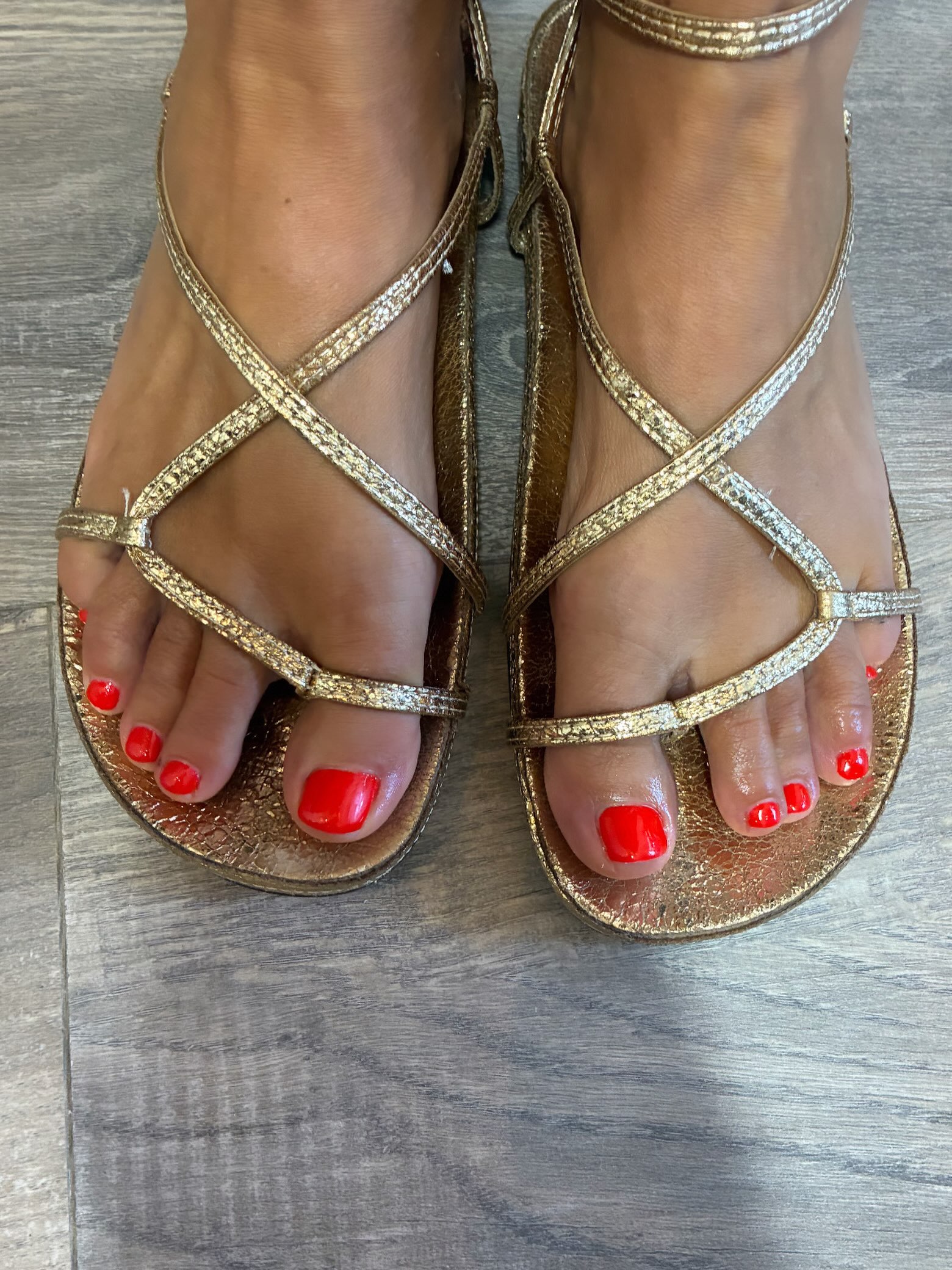 Rood gelakte teennagels in gouden sandalen